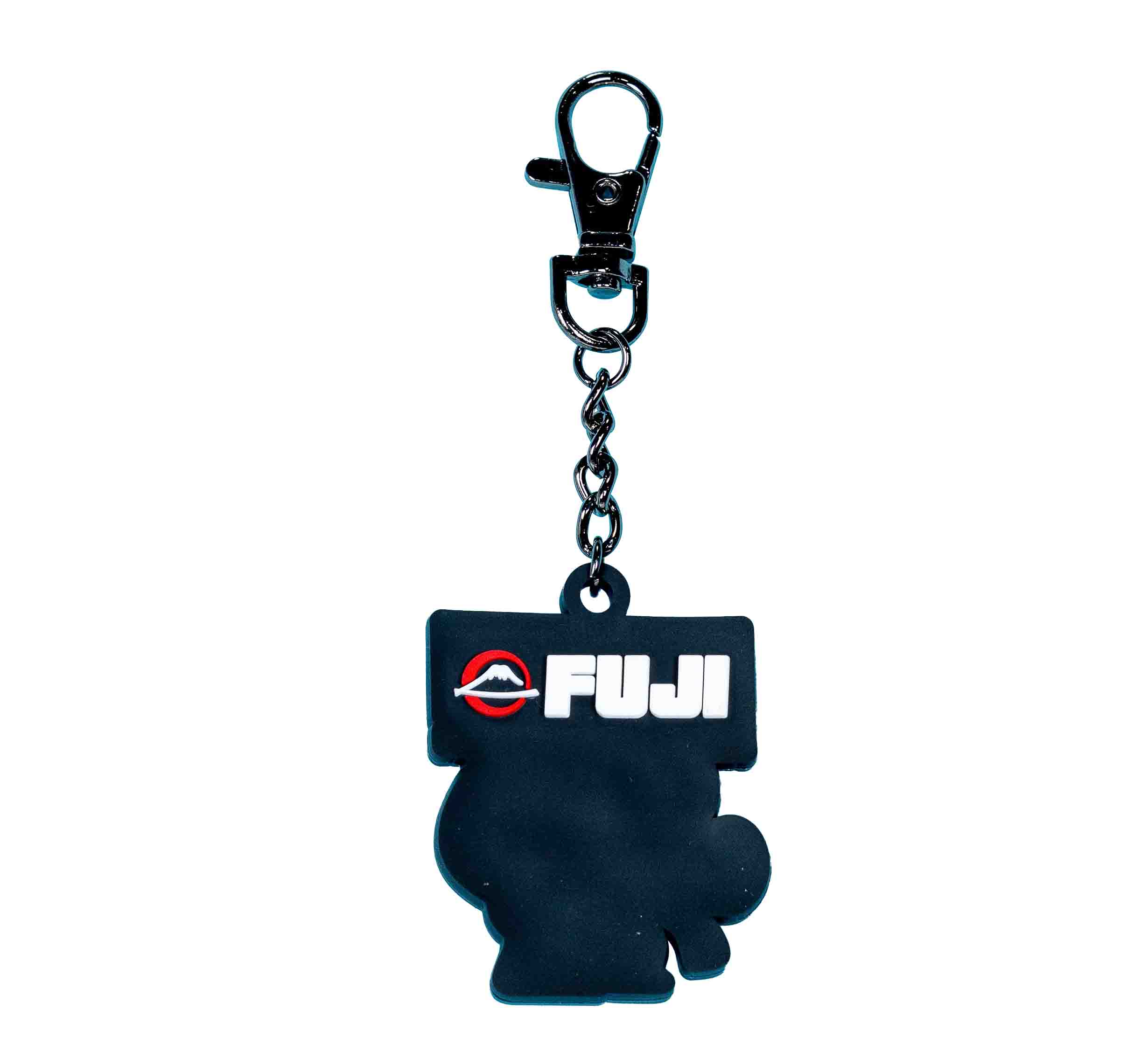 The FUJI Kimono Keychain White is a black keychain with a metal clip, featuring "FUJI" in bold white letters, a red and white logo above the text, and an abstract shape below.