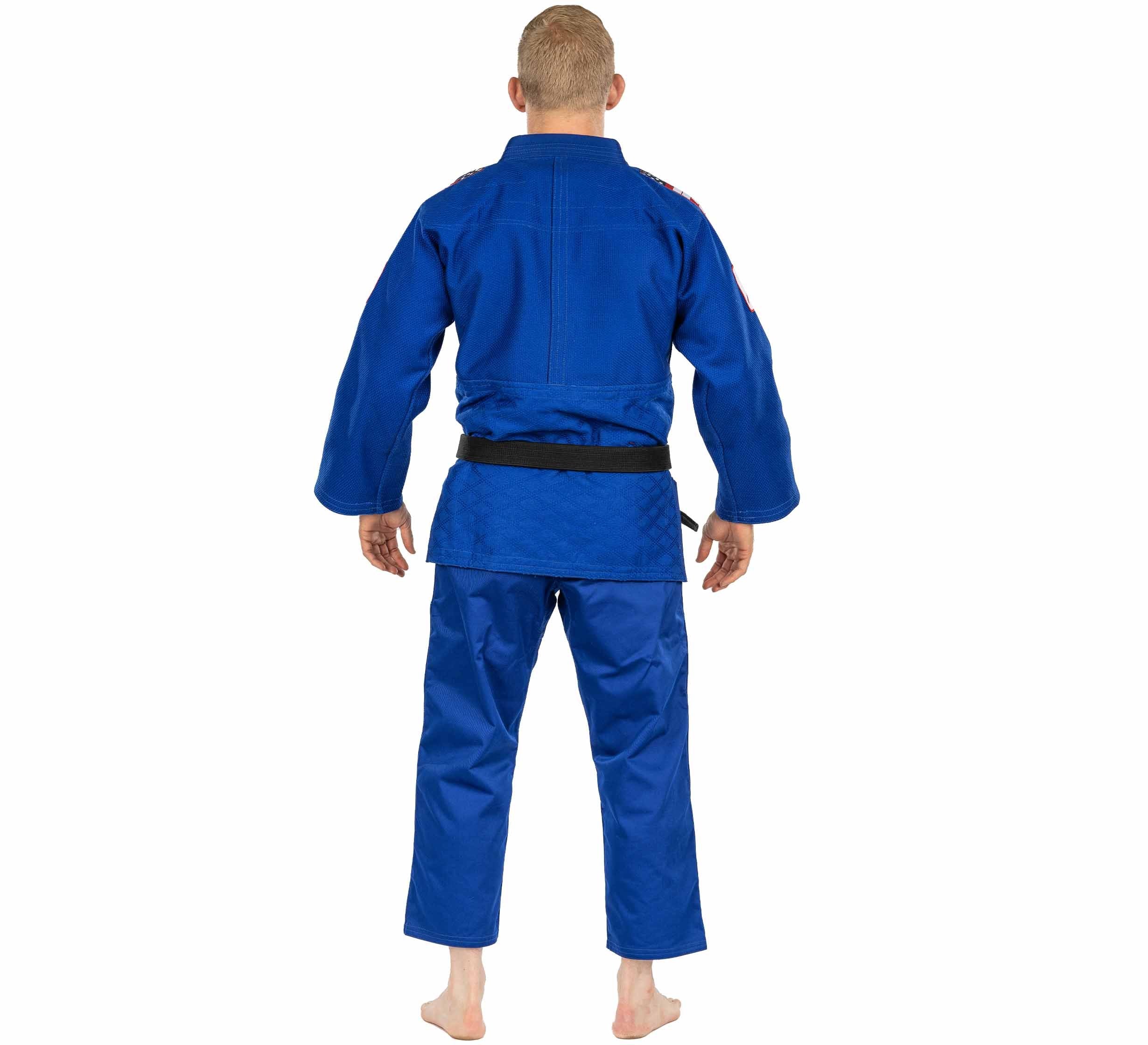 A barefoot person with short blond hair, wearing the USA Judo Double Weave Gi 2.0 Blue and a black belt, stands facing away on a plain white background.