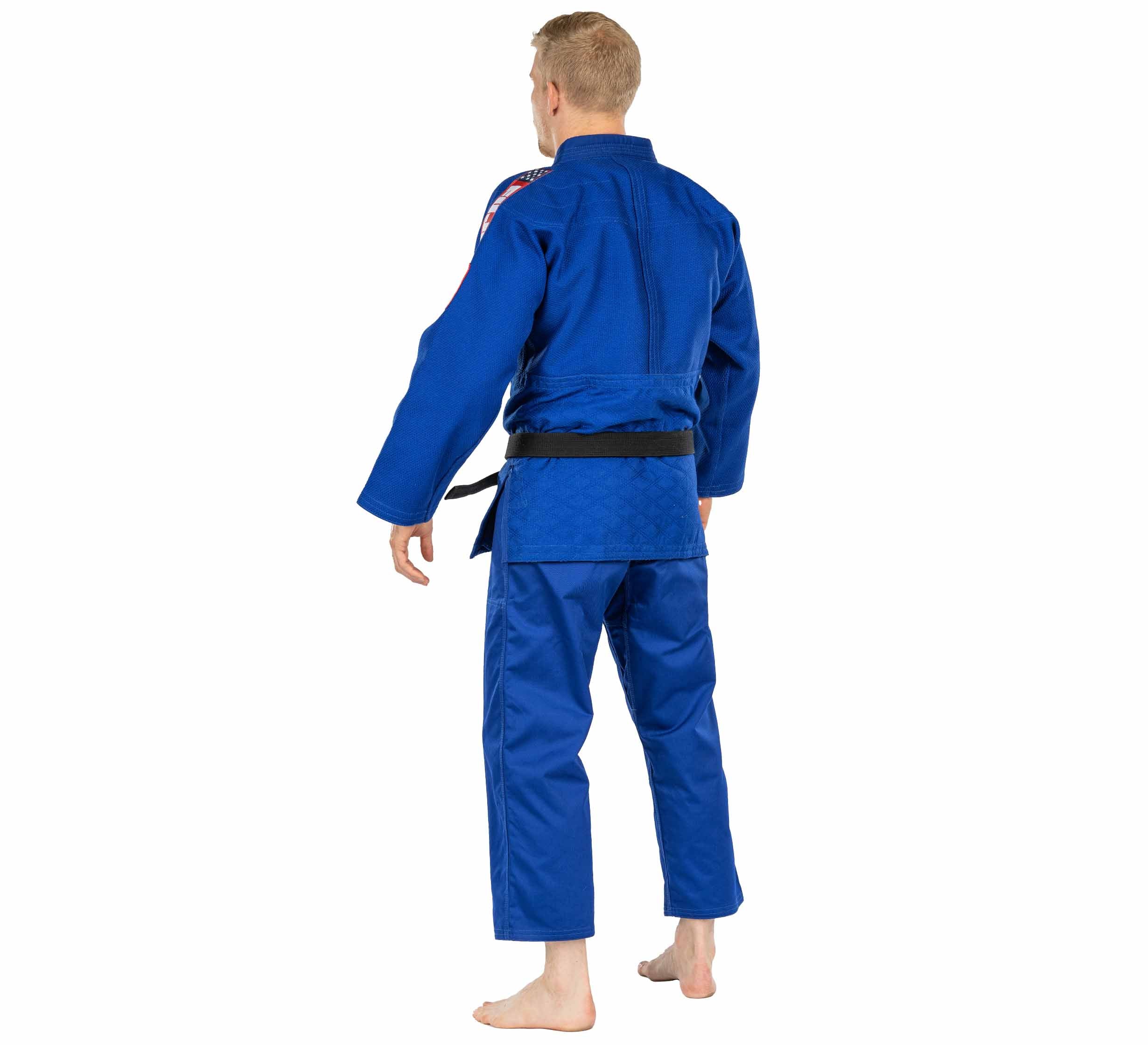 A person stands barefoot, facing away from the camera against a plain white background, wearing the USA Judo Single Weave Gi 2.0 Blue with a black belt.
