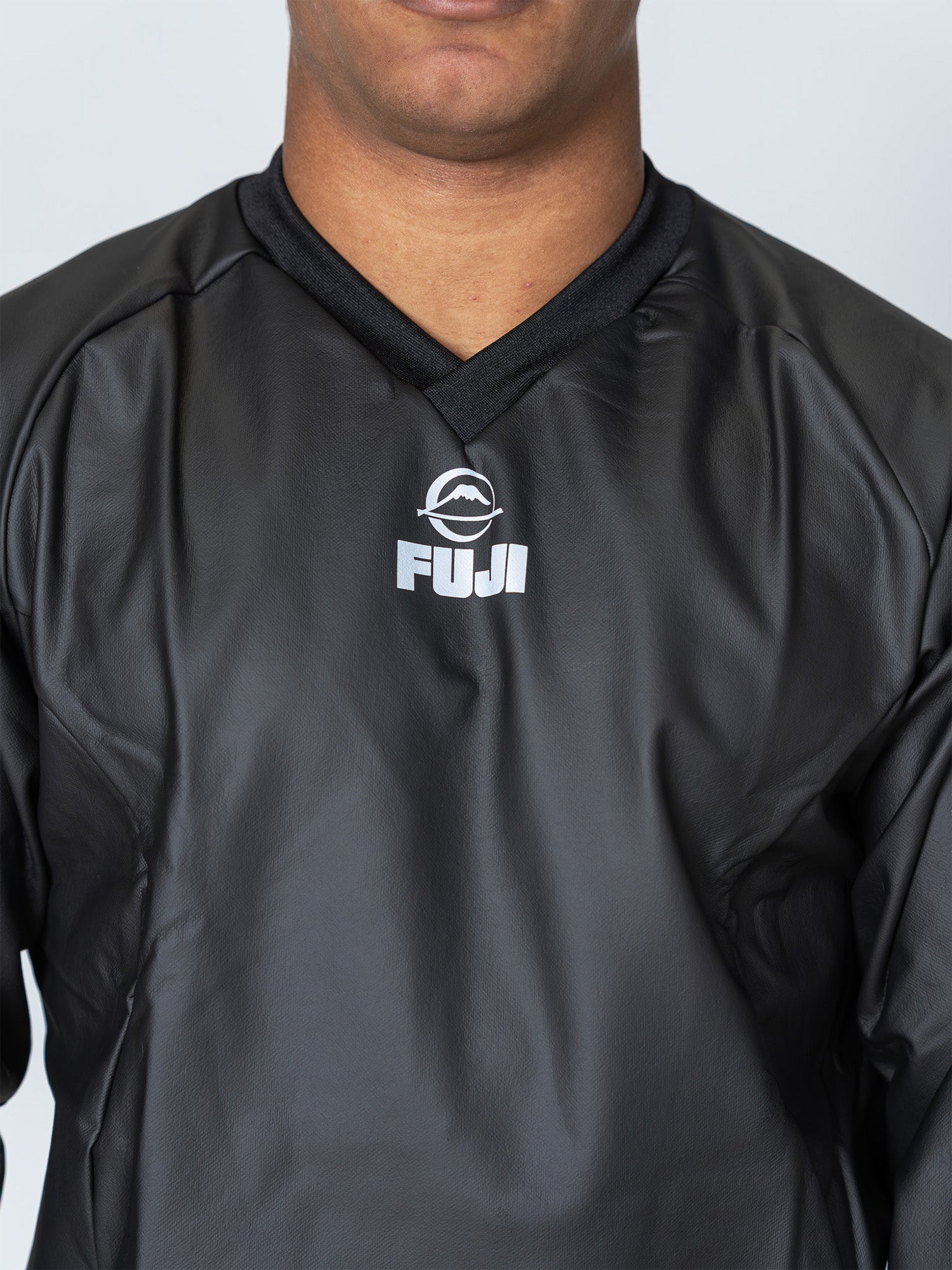 A person wearing the black Grappling Sauna Suit with a white FUJI logo on the chest; the photo is cropped from shoulders to mouth, showing only the lower face and upper torso.